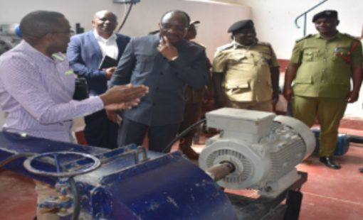 Kilimajaro Regional Commissioner hon. Stephen Kagaigai (2nd left) being briefed by PIU chairperson Dr. Erick Mgaya on how a mini hydro turbine made at ATC works when he visited Kikuletwa campus